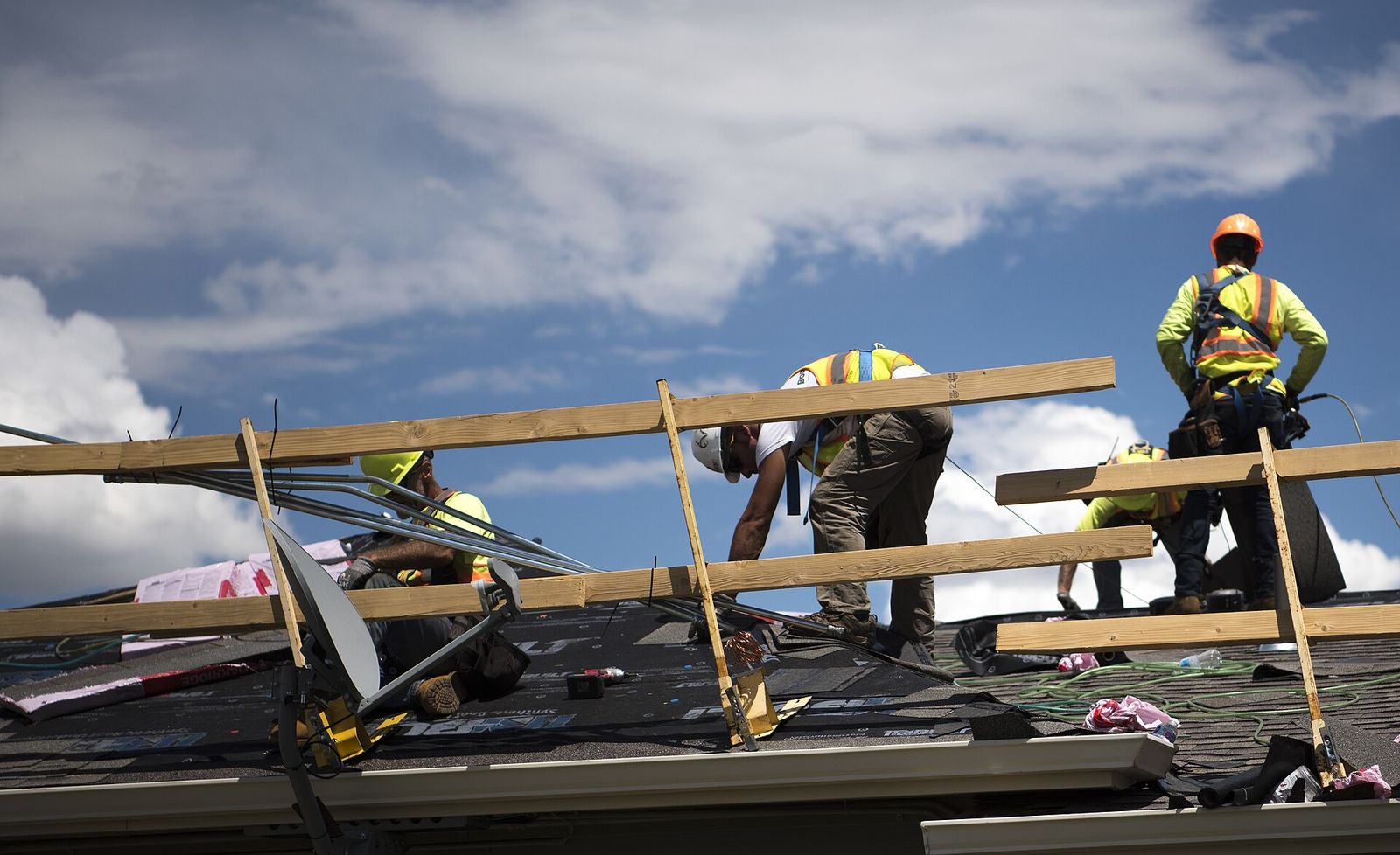Roofing crew on a ridge under a big sky, setting trusses and sheathing