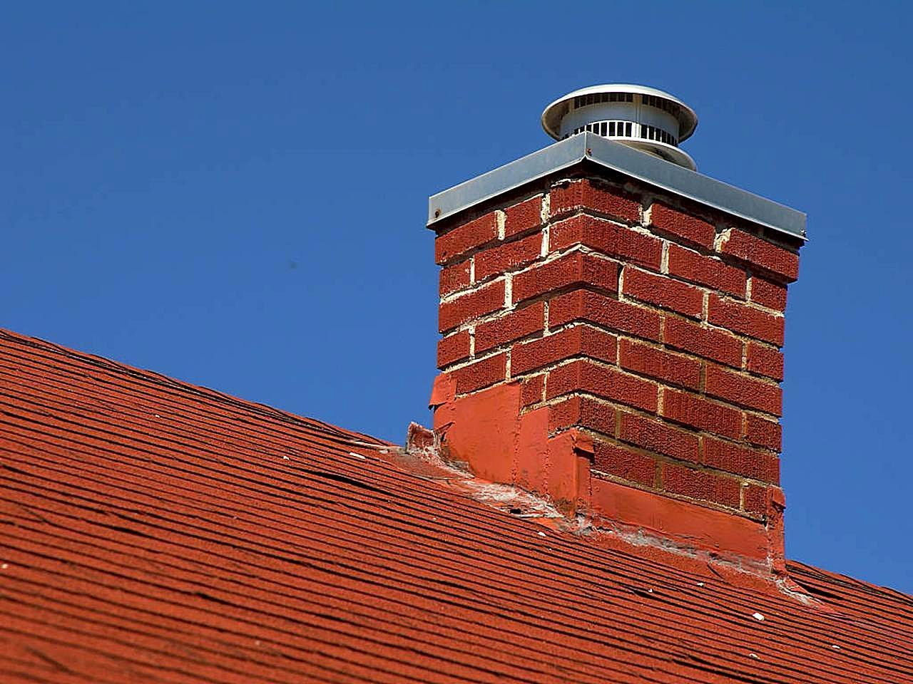 Red brick chimney on a steep roof against a blue sky
